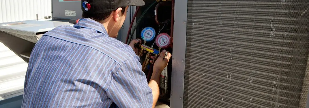 HVAC technician servicing a condenser unit in Canton